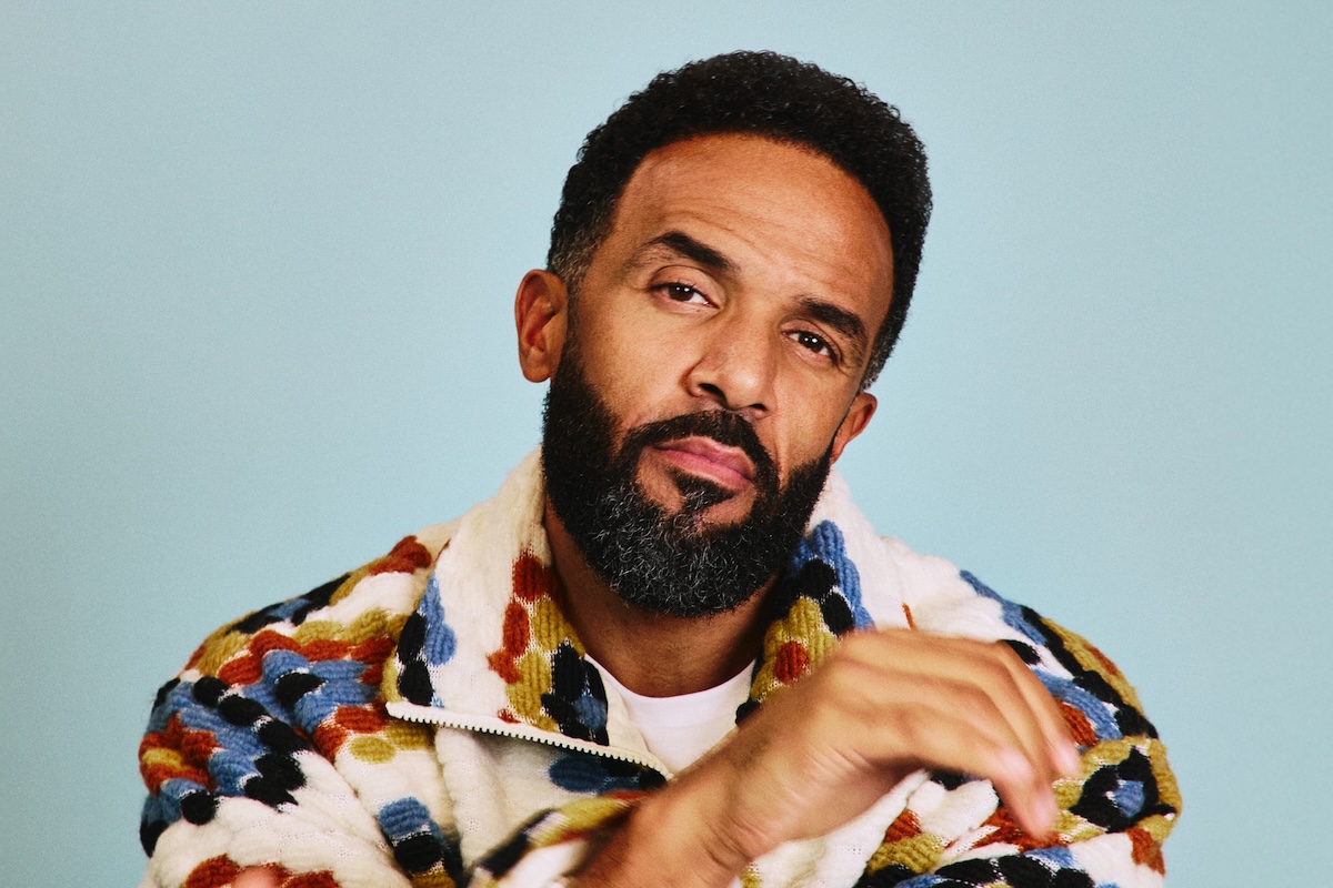 Portrait of singer-songwriter Craig David wearing a patterned fleece jacket against a light blue backdrop.